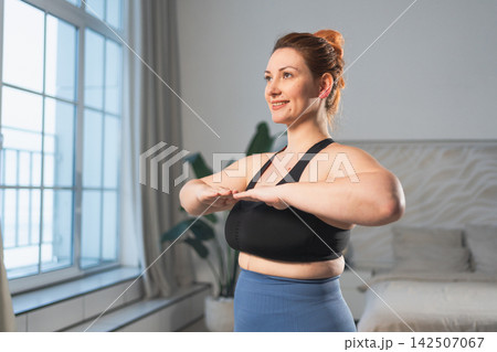 Fitness workout training. Woman practicing fitness at home. Plus size female doing sports exercise at home indoor. Girl in sportswear have workout weight training for weight loss. Sport and fitness Fitness workout training. Woman practicing fitness at home. Plus size female doing sports exercise at home indoor. Girl in sportswear have workout weight training for weight loss. Sport and fitness 142507067