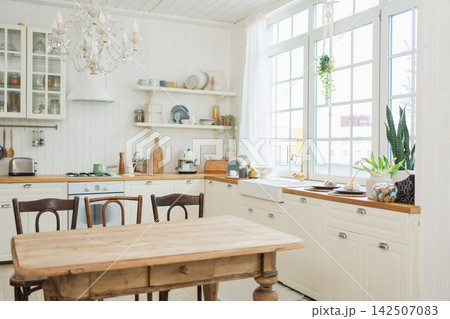 Empty white wooden kitchen interior with dining room. Scandinavian classic minimalistic bright kitchen with white and wooden details. Modern white kitchen clean contemporary style interior design 142507083