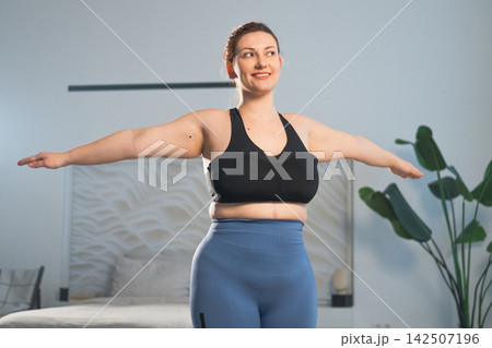 Fitness workout training. Woman practicing fitness at home. Plus size female doing sports exercise at home indoor. Girl in sportswear have workout weight training for weight loss. Sport and fitness Fitness workout training. Woman practicing fitness at home. Plus size female doing sports exercise at home indoor. Girl in sportswear have workout weight training for weight loss. Sport and fitness 142507196