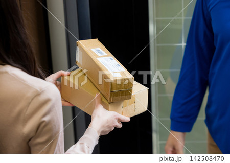玄関で荷物を渡す配達員 玄関で荷物を渡す配達員 142508470