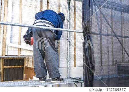 外壁リフォームで重ね張り用の下地を施工する男性職人 外壁リフォームで重ね張り用の下地を施工する男性職人 142509877