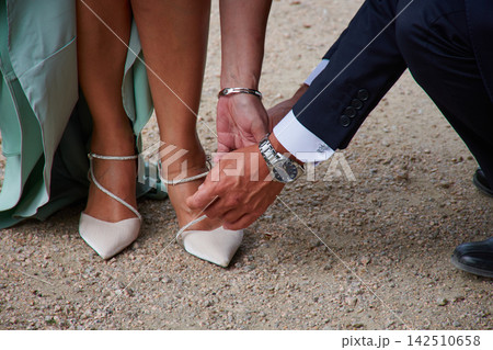 Romantic gesture of the groom adjusting the bride's elegant mint green shoes on their wedding day Romantic gesture of the groom adjusting the bride's elegant mint green shoes on their wedding day 142510658