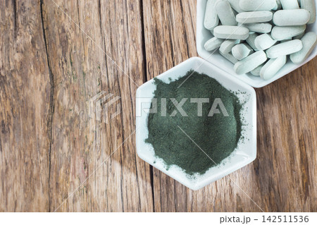 Spirulina powder and tablets on wooden background 142511536