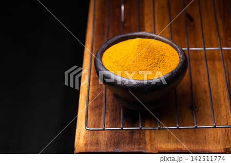 Turmeric Powder in a Wooden Spoon and Bowl Turmeric Powder in a Wooden Spoon and Bowl 142511774