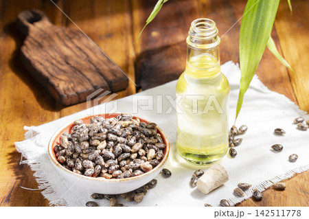 castor seeds and oil, on wooden surface, royalty free 142511778