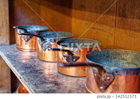 Vintage Copper Saucepans Lined Up on Rustic Wooden Shelf 142512373