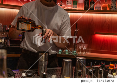 Bartender pouring whiskey in stylish bar setting Bartender pouring whiskey in stylish bar setting 142513678