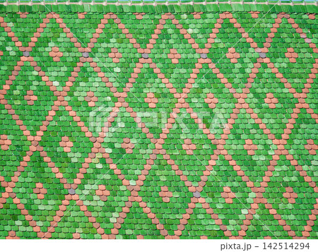 Close-up of a traditional colorful tiled roof in Alsace, France, featuring a decorative pattern of green and terracotta roof tiles. 142514294