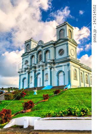 Scenic view of the Notre-Dame de l'Assomption church on a grassy hill under a cloudy blue sky in Sainte-Marie, Martinique, Caribbean France 142514502