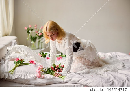 Peaceful setting with fair woman placing blooming tulips in sunlight 142514717