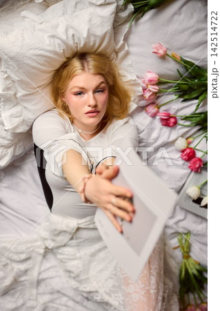 Caucasian woman enjoying morning with pink tulips and linens Caucasian woman enjoying morning with pink tulips and linens 142514722