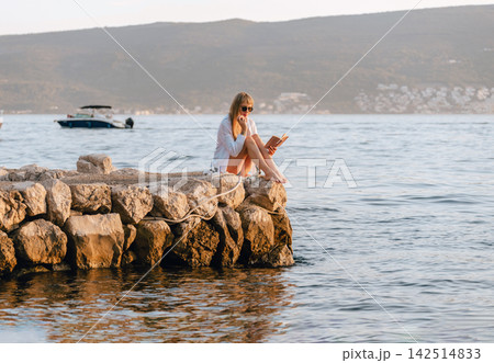Local European Woman Reading Paper Book on Pier 142514833