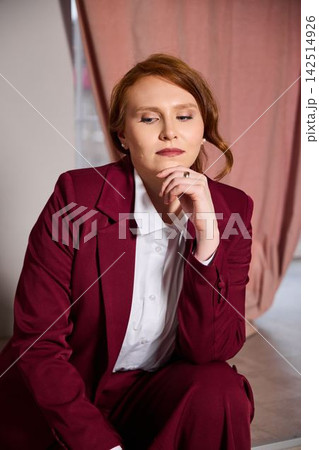 Contemplative redhead female dressed professionally in studio setting Contemplative redhead female dressed professionally in studio setting 142514926