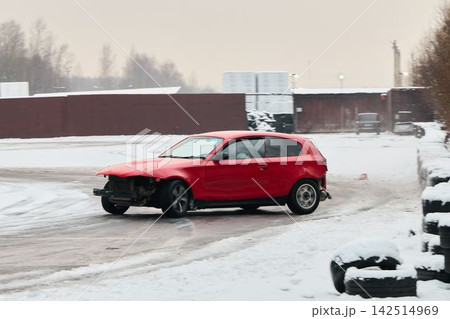 Profile view of red car braking on icy winding road with snow spray Profile view of red car braking on icy winding road with snow spray 142514969