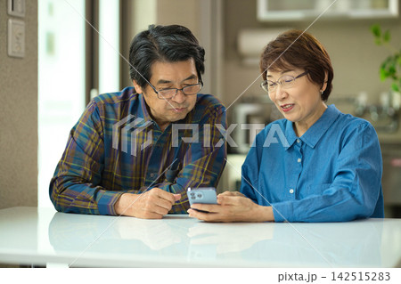 リビングで一緒にスマホを見るシニアの夫婦 142515283