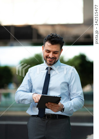 Businessman using tablet, smiling, working outdoors with technology Businessman using tablet, smiling, working outdoors with technology 142515477