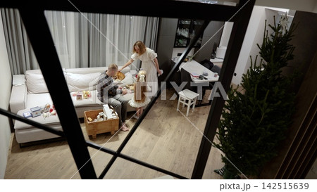 Family unpacking festive christmas decorations, smiling and sharing joyful moments while decorating living room with sparkling ornaments and creating cozy holiday spirit 142515639