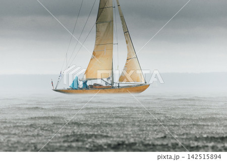 vintage wooden Dragon class sailing yacht at heavy rain, sailing regatta in the Gulf of Finland, Yachtsmen are sitting amicably on board of the sailing boat, teamwork 142515894