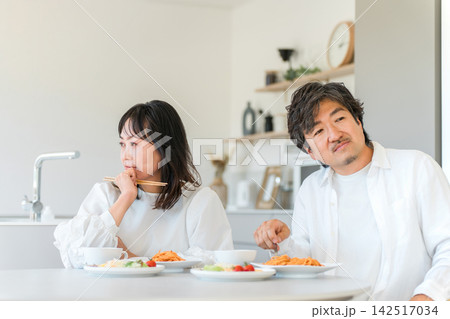 食事中に気まずい空気が流れる40代夫婦。夫婦喧嘩やすれ違いに悩む家庭 食事中に気まずい空気が流れる40代夫婦。夫婦喧嘩やすれ違いに悩む家庭 142517034