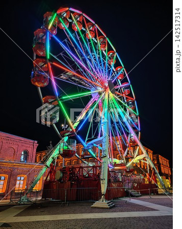 Illuminated Ferris Wheel with Colorful Rainbow LED Lights at Christmas Night on City Square 142517314