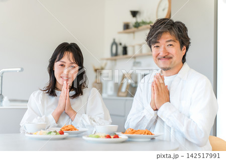 食事の前にいただきますをする40代夫婦。笑顔で食卓を囲む仲の良い二人 食事の前にいただきますをする40代夫婦。笑顔で食卓を囲む仲の良い二人 142517991