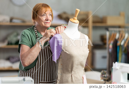 Woman seamstress adjusts clothes on mannequin 142518063