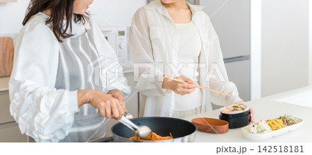 キッチンで弁当を作る母と娘。笑顔で楽しむ親子の料理時間 キッチンで弁当を作る母と娘。笑顔で楽しむ親子の料理時間 142518181