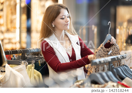 European woman choosing a warm sweater in a shopping mall European woman choosing a warm sweater in a shopping mall 142518244