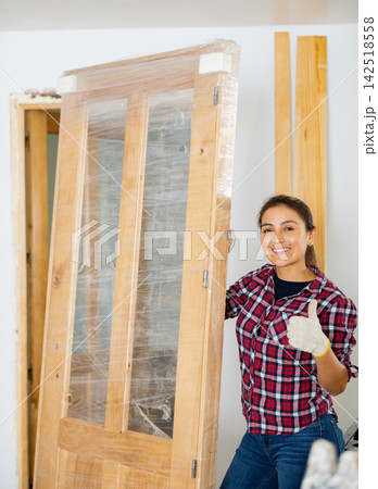Portrait of positive woman with new door in apartment Portrait of positive woman with new door in apartment 142518558