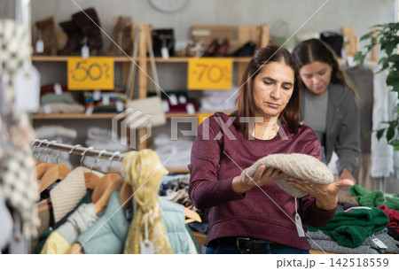 Latina woman chooses demi-season hat in clothing store. Latina woman chooses demi-season hat in clothing store. 142518559