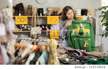 Young woman chooses sweater in clothing store Young woman chooses sweater in clothing store 142518628