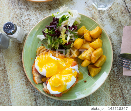 Portion of eggs benedict toast with salmon and potatoes closeup Portion of eggs benedict toast with salmon and potatoes closeup 142518847