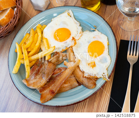 Delicious breakfast - scrambled eggs with bacon and french fries closeup 142518875