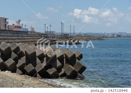 快晴の空と遠くに街灯のある公園が見える消波ブロックの並ぶ防波堤の海岸 快晴の空と遠くに街灯のある公園が見える消波ブロックの並ぶ防波堤の海岸 142518946