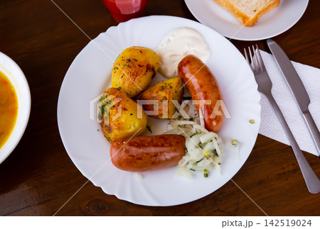 Grilled meat sausages served with potatoes fried with onion Grilled meat sausages served with potatoes fried with onion 142519024
