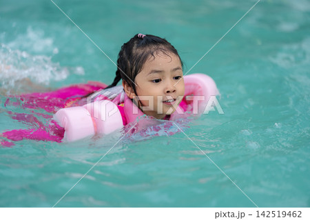 preschool child girl playing and swimming with floaties in pool water preschool child girl playing and swimming with floaties in pool water 142519462