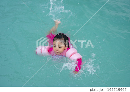 preschool child girl playing and swimming with floaties in pool water preschool child girl playing and swimming with floaties in pool water 142519465