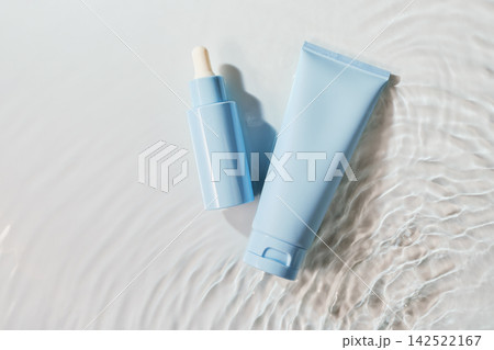 Skincare serum dropper bottle and moisturizer tube floating on water with ripples Skincare serum dropper bottle and moisturizer tube floating on water with ripples 142522167