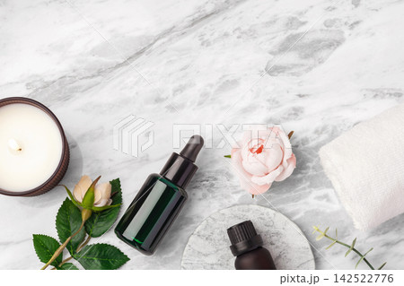 Green oil serum dropper bottle, essential oil bottle, burning candle and pink rose flowers on marble table background, top view Green oil serum dropper bottle, essential oil bottle, burning candle and pink rose flowers on marble table background, top view 142522776