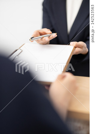 書類とペンを手渡すスーツを着た女性の手元のクローズアップ 書類とペンを手渡すスーツを着た女性の手元のクローズアップ 142523563