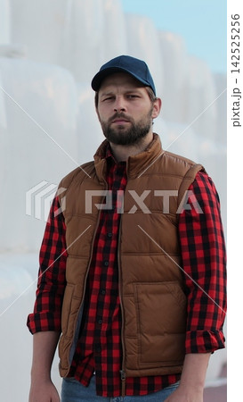 Vertical video. Portrait of a young farmer in work attire posing by hay stack. Modern organic agriculture. Vertical video. Portrait of a young farmer in work attire posing by hay stack. Modern organic agriculture. 142525256