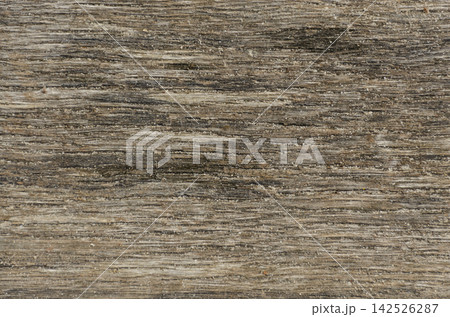 Weathered driftwood texture with fine sand grains. Aged natural wood background ideal for eco branding, beach themes, and rustic web design Weathered driftwood texture with fine sand grains. Aged natural wood background ideal for eco branding, beach themes, and rustic web design 142526287