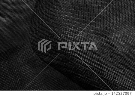 Crumpled black fiberglass mosquito net fabric. Modern abstract dark background with grid pattern Crumpled black fiberglass mosquito net fabric. Modern abstract dark background with grid pattern 142527097