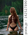 Serene woman with long wet hair in crochet top bathing in forest lake 142527890