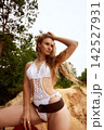 Confident woman in white knit swimsuit and brown belt posing on sandy hill 142527931
