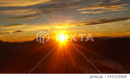 山の稜線から差し込む光条の夕日 山の稜線から差し込む光条の夕日 142529008