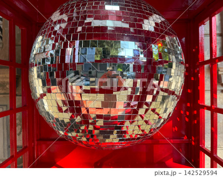 Disco ball inside a red phone booth in an urban area during daytime Disco ball inside a red phone booth in an urban area during daytime 142529594