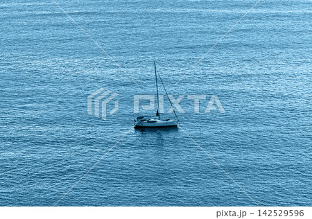 Sailboat floats on the water near the coast during daytime in a clear sky Sailboat floats on the water near the coast during daytime in a clear sky 142529596
