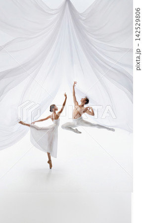 Joyful ballet pair performs contrasting leaps beneath fabric canopy Joyful ballet pair performs contrasting leaps beneath fabric canopy 142529806