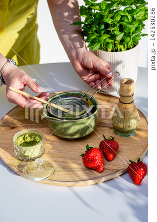 Hands Whisking Matcha to Frothy Consistency with Strawberries Hands Whisking Matcha to Frothy Consistency with Strawberries 142530286